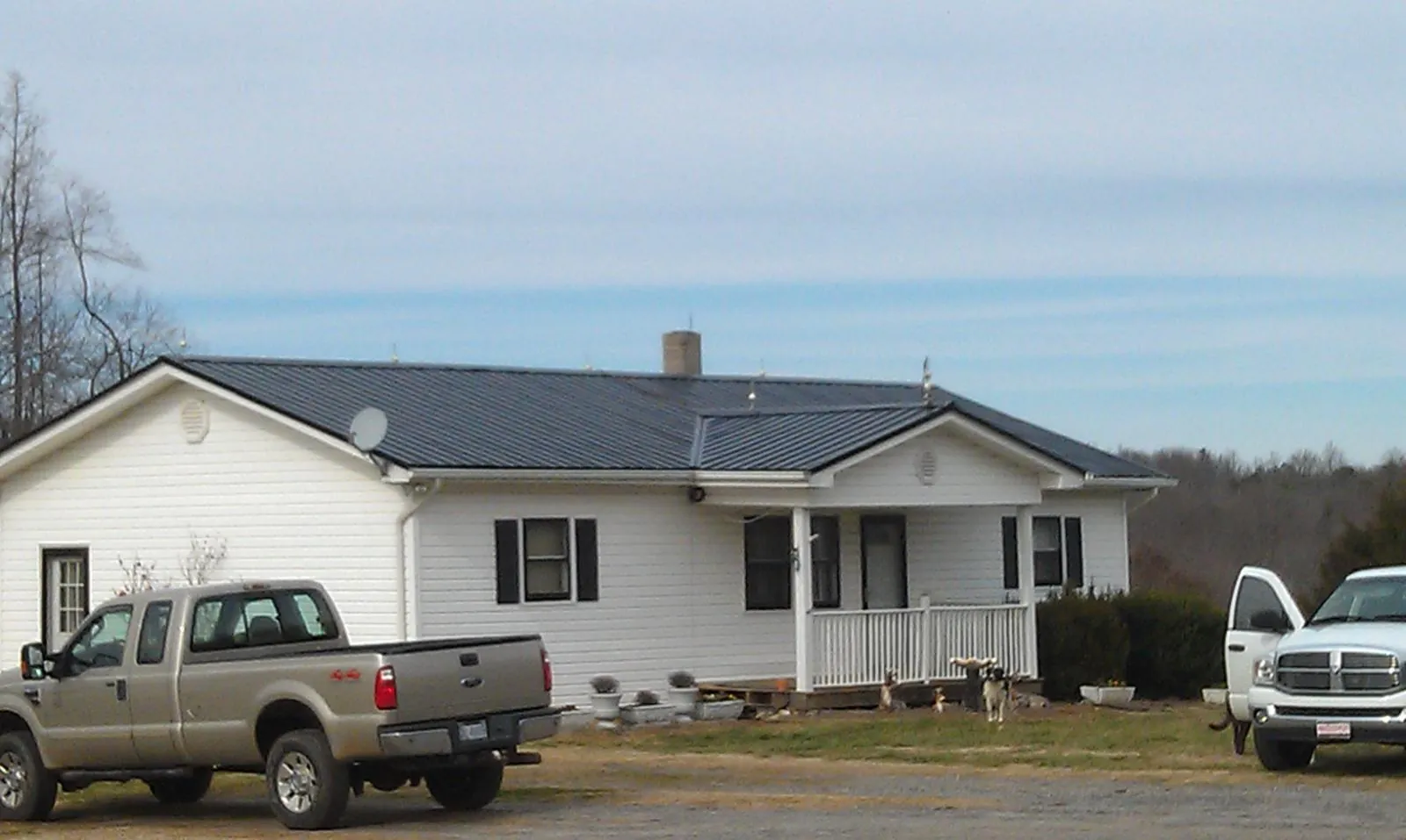 Finished dark metal roof on a white ranch home with work trucks parked in Marietta